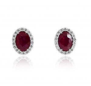 A pair of oval ruby and diamond halo studs