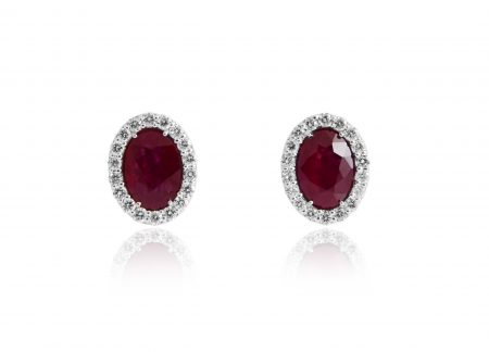 A pair of oval ruby and diamond halo studs
