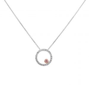 An 18K White Gold Diamond Circle Pendant with a pink diamond, set with 26 Round Brilliant Cut diamonds equaling 0.27ct and the pink diamond 0.051ct set in a bezel setting 18K Rose GoldCarat: Diamonds 26 = 0.27ct Pink Diamond 1 = 0.27ct